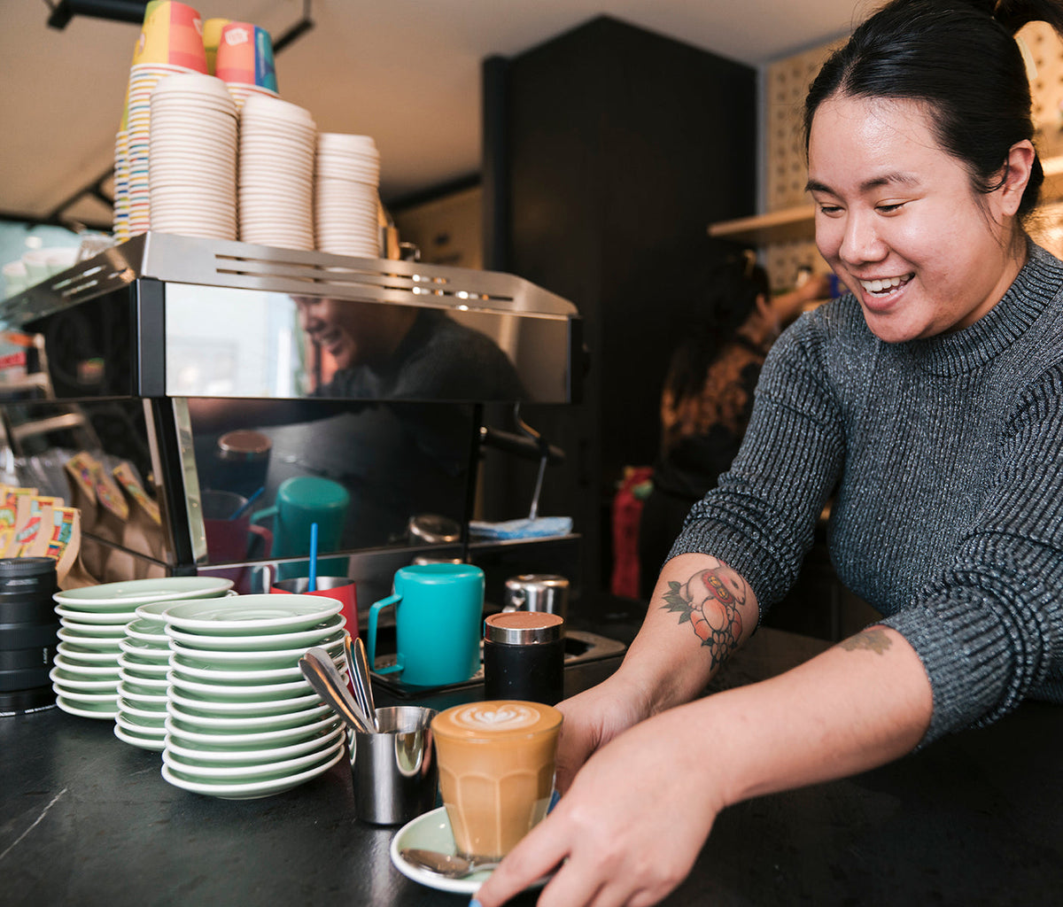 Barista setting down a flat white at the on-site cafe at Goodspace Kingsgrove, a workspace with a cafe in Sydney