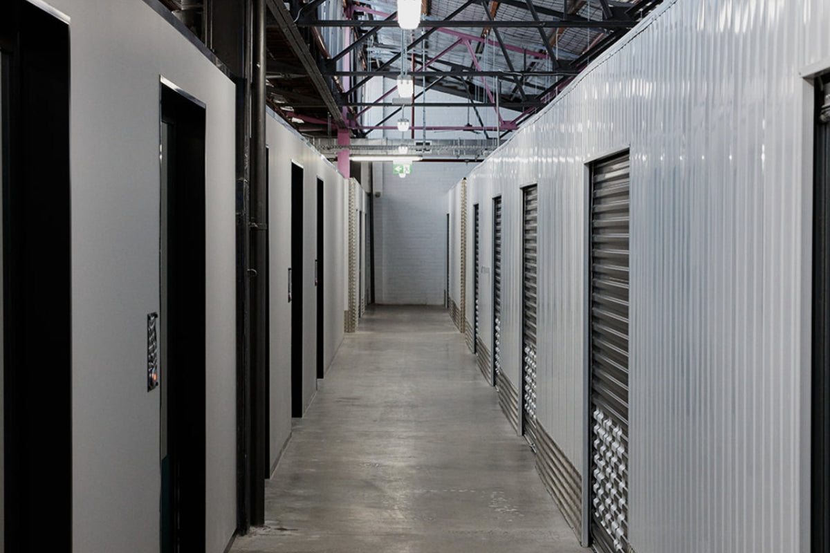Corridor of white warehouse spaces with black roller doors at Goodspace Kingsgrove