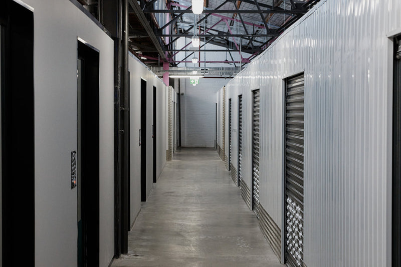 Corridor of white warehouse spaces with black roller doors at Goodspace Kingsgrove