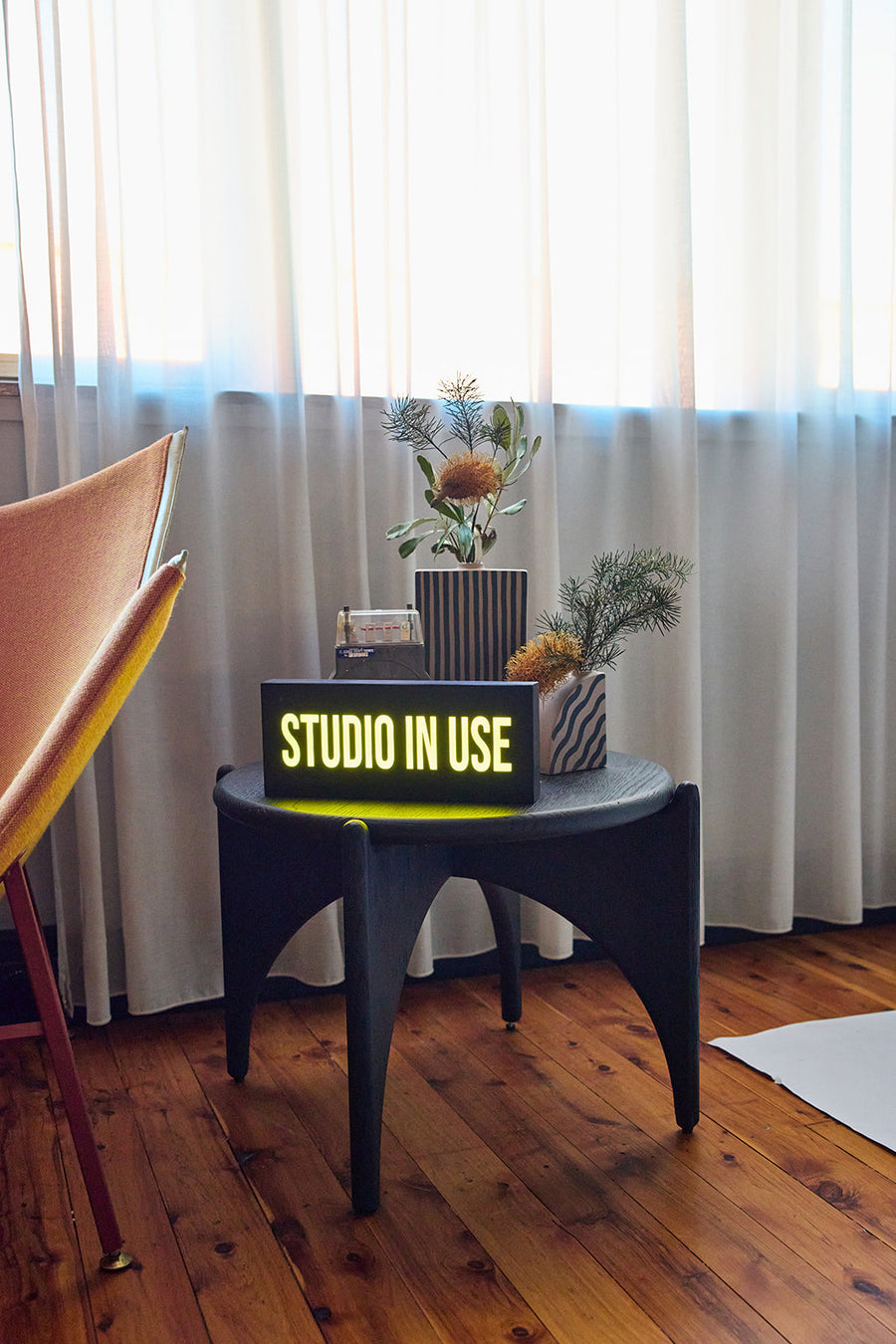 Illuminated studio-in-use sign on a side table by a curtained window at Goodspace Kingsgrove