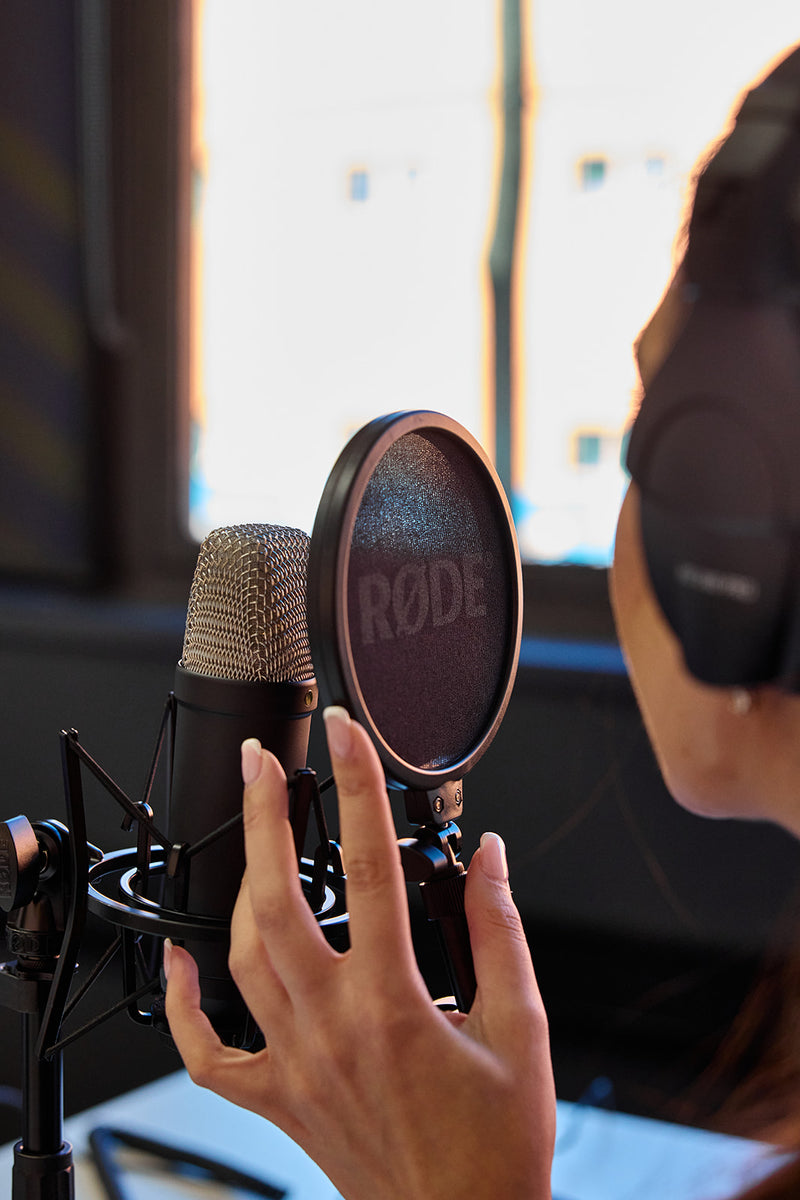A woman recording into a RØDE condenser microphone with a pop filter at Goodspace Kingsgrove