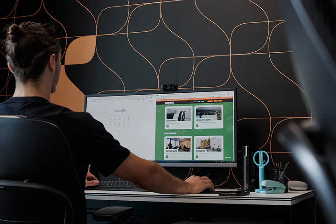 Working at a corporate office desk against a dark feature wall at Goodspace Kingsgrove