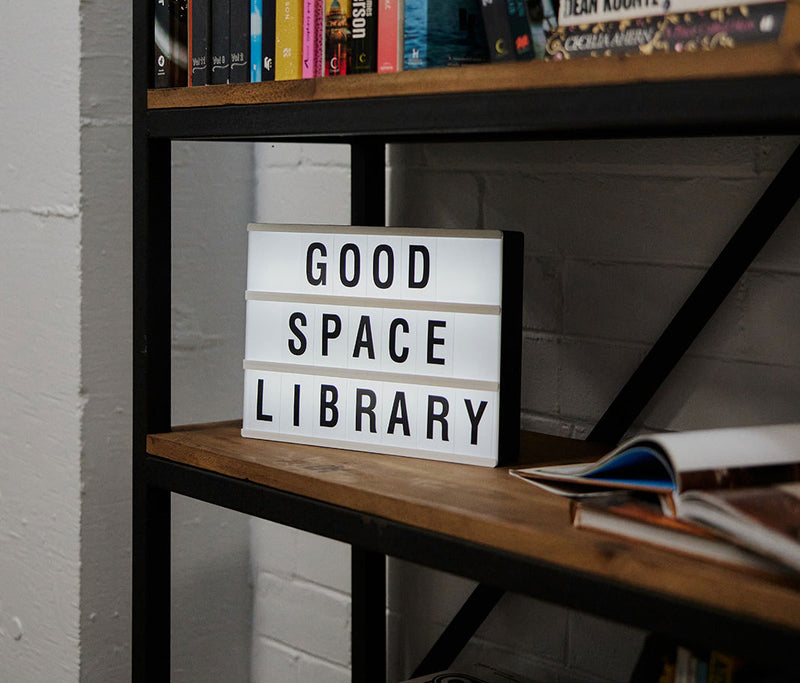 The community book swap shelf at Goodspace Kingsgrove with a Good Space Library lightbox sign