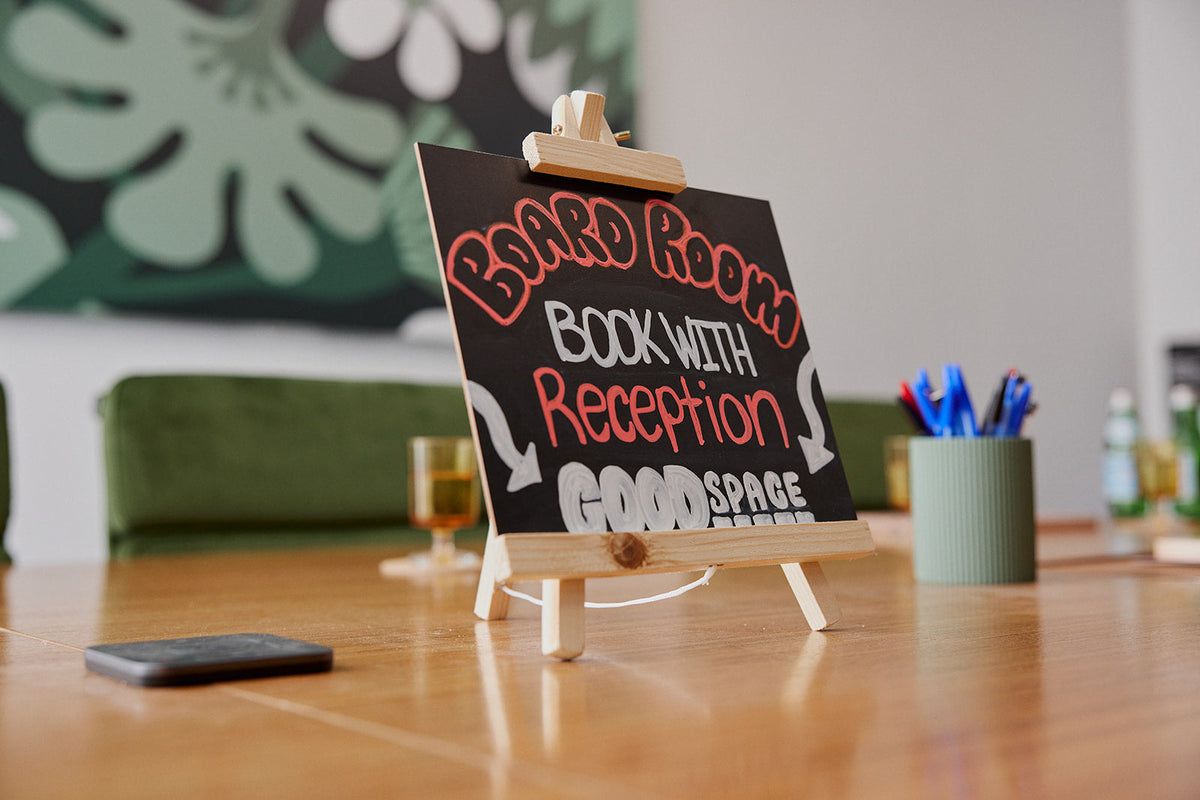 Chalkboard sign on the boardroom table at Goodspace Kingsgrove reading Board Room, book with reception