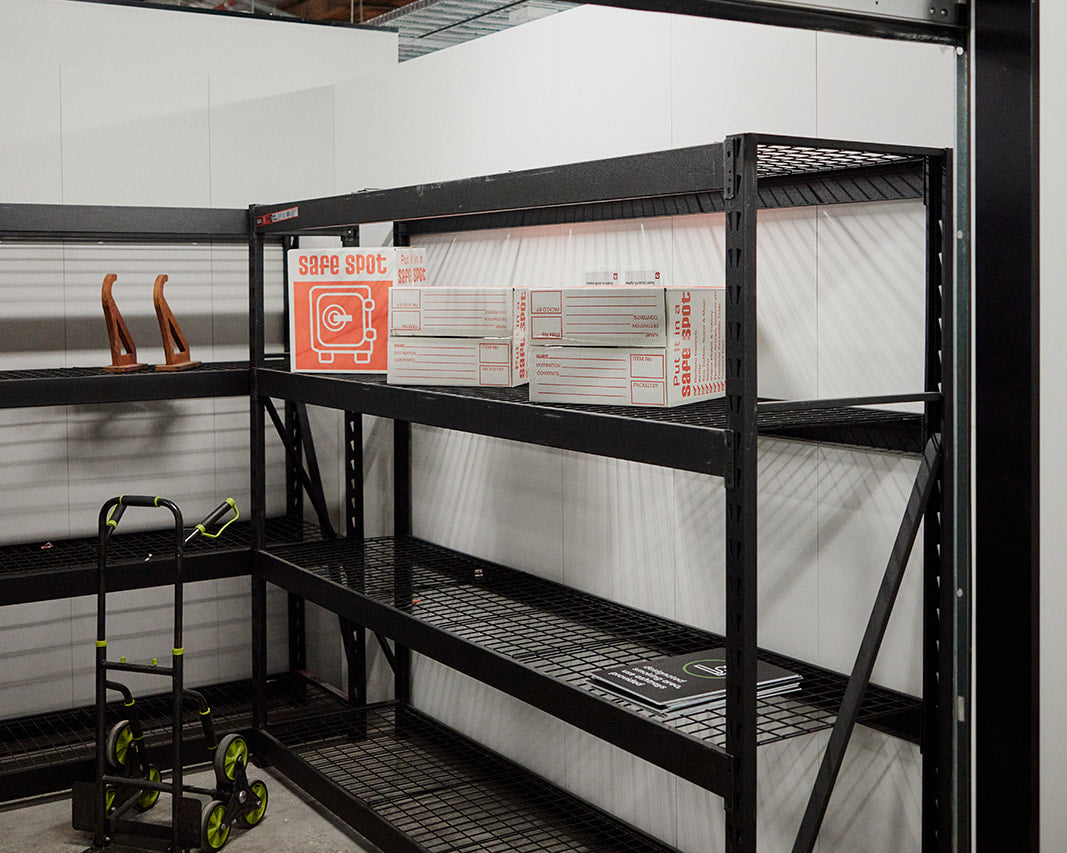 Packing station with black shelving, packing boxes and a hand trolley at the Kingsgrove E-Comm Hub