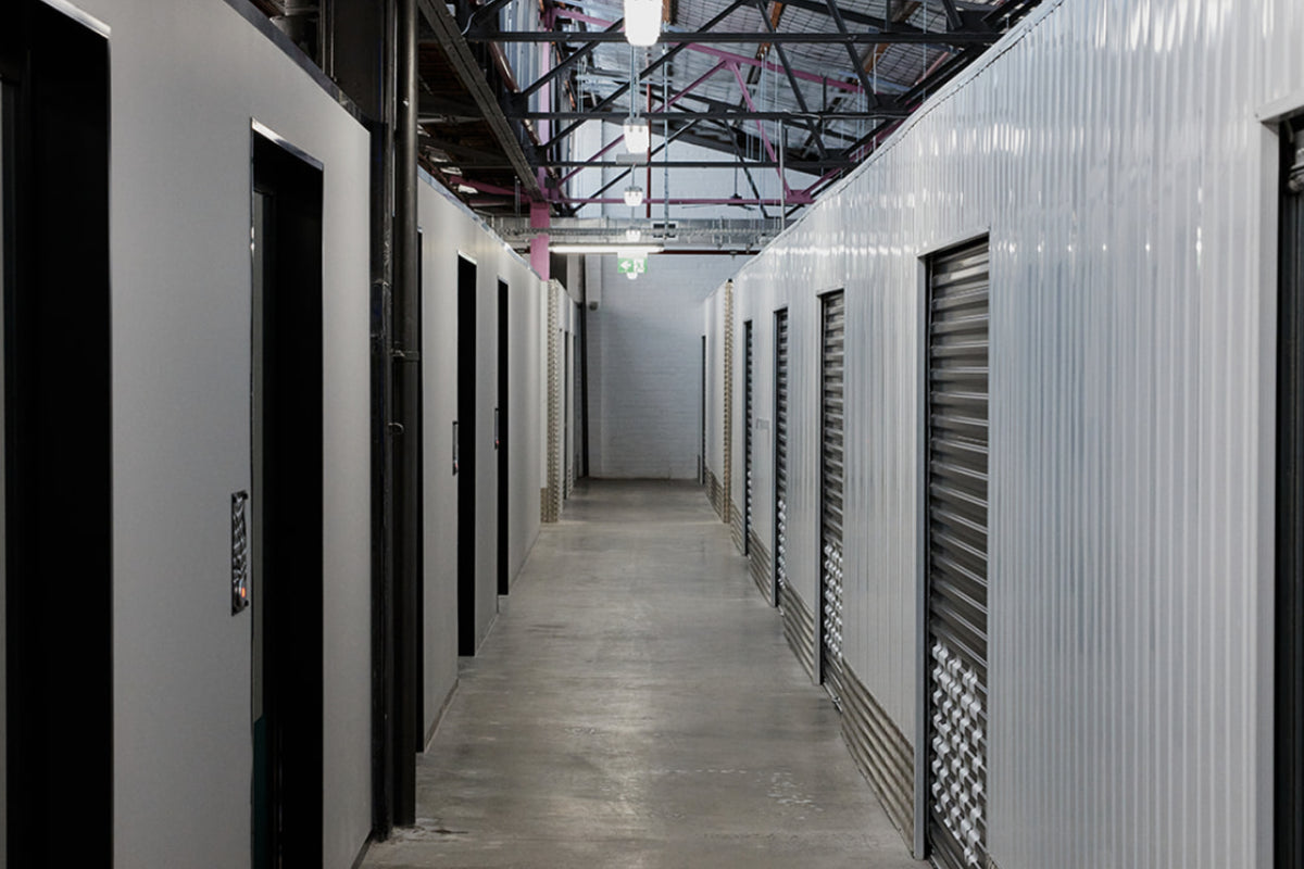 Corridor of white warehouse spaces with black roller doors at Goodspace Kingsgrove